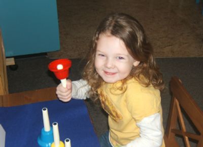 little girl holding a red bell