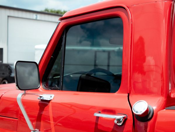 Close-up of a red truck door and window with side mirror.