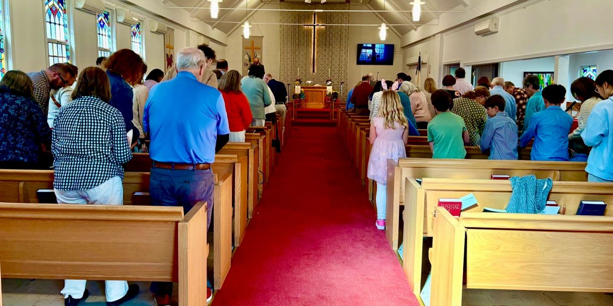 People standing in a church during a service, facing the altar.
