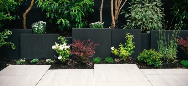 Concrete slab retaining wall, privacy screen, porcelain slab patio, fire pit, artificial turf lawn 