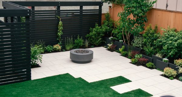 Concrete slab retaining wall, privacy screen, porcelain slab patio, fire pit, artificial turf lawn 