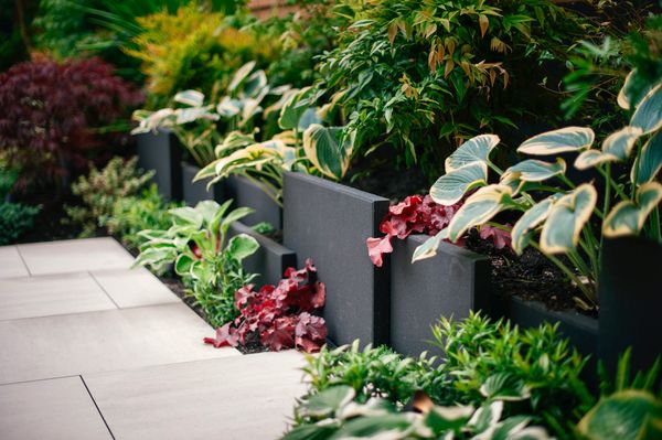 Concrete slab retaining wall, privacy screen, porcelain slab patio, fire pit, artificial turf lawn 