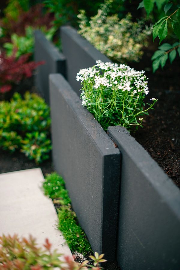 Concrete slab retaining wall, privacy screen, porcelain slab patio, fire pit, artificial turf lawn 