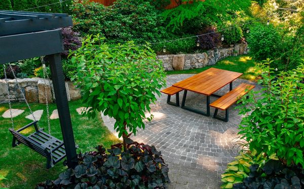 Basalt stone retaining wall, stone stair tread, pergola, lawn area, bluestone stepping stone walkway