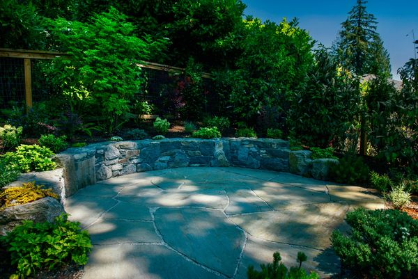 Basalt stone retaining wall and bench, pennsylavnia bluestone patio, flagstone patio, planting.