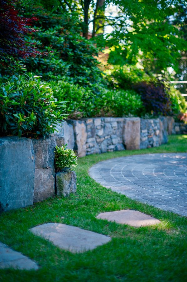 Basalt stone retaining wall, outdoor dining, lawn area, bluestone stepping stone walkway, front yard