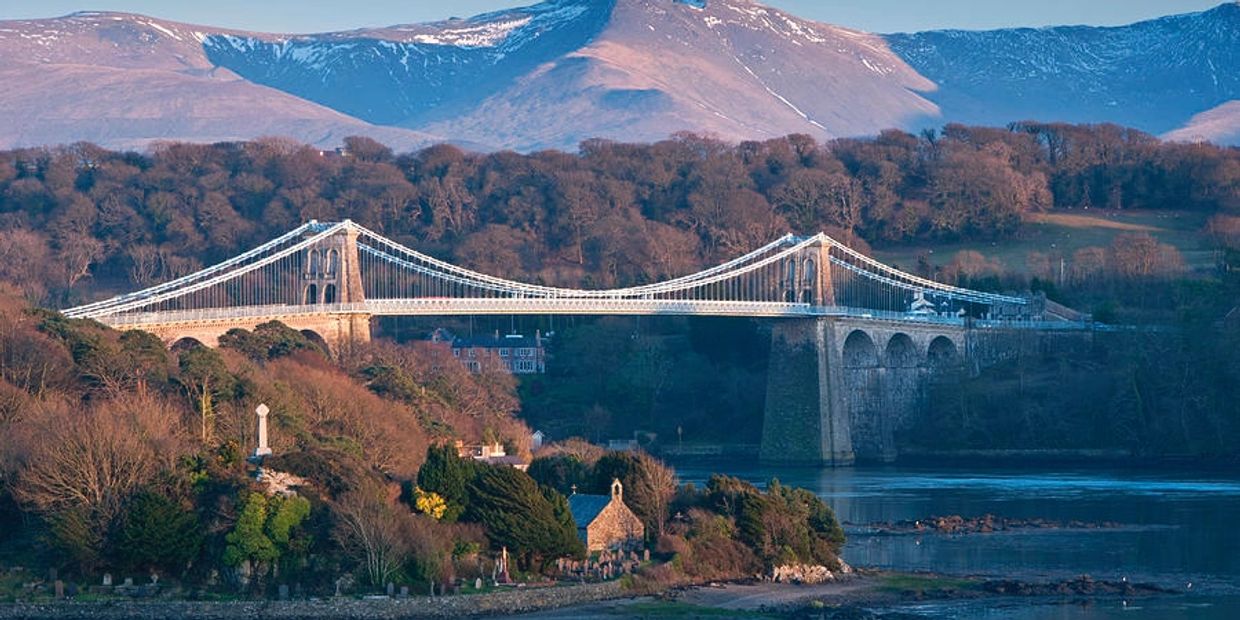 menai bridge in sunset with mountains behind