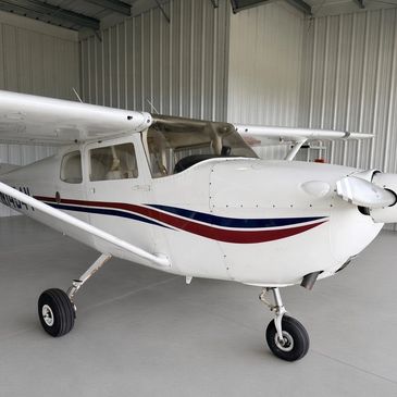 Small white single-engine airplane in hangar.