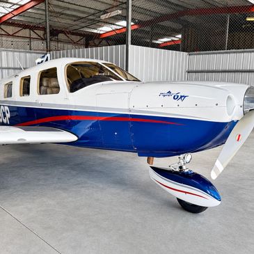 Small blue and white single-engine airplane inside a hangar.