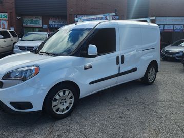 White RAM ProMaster City van parked outside an auto sales lot.