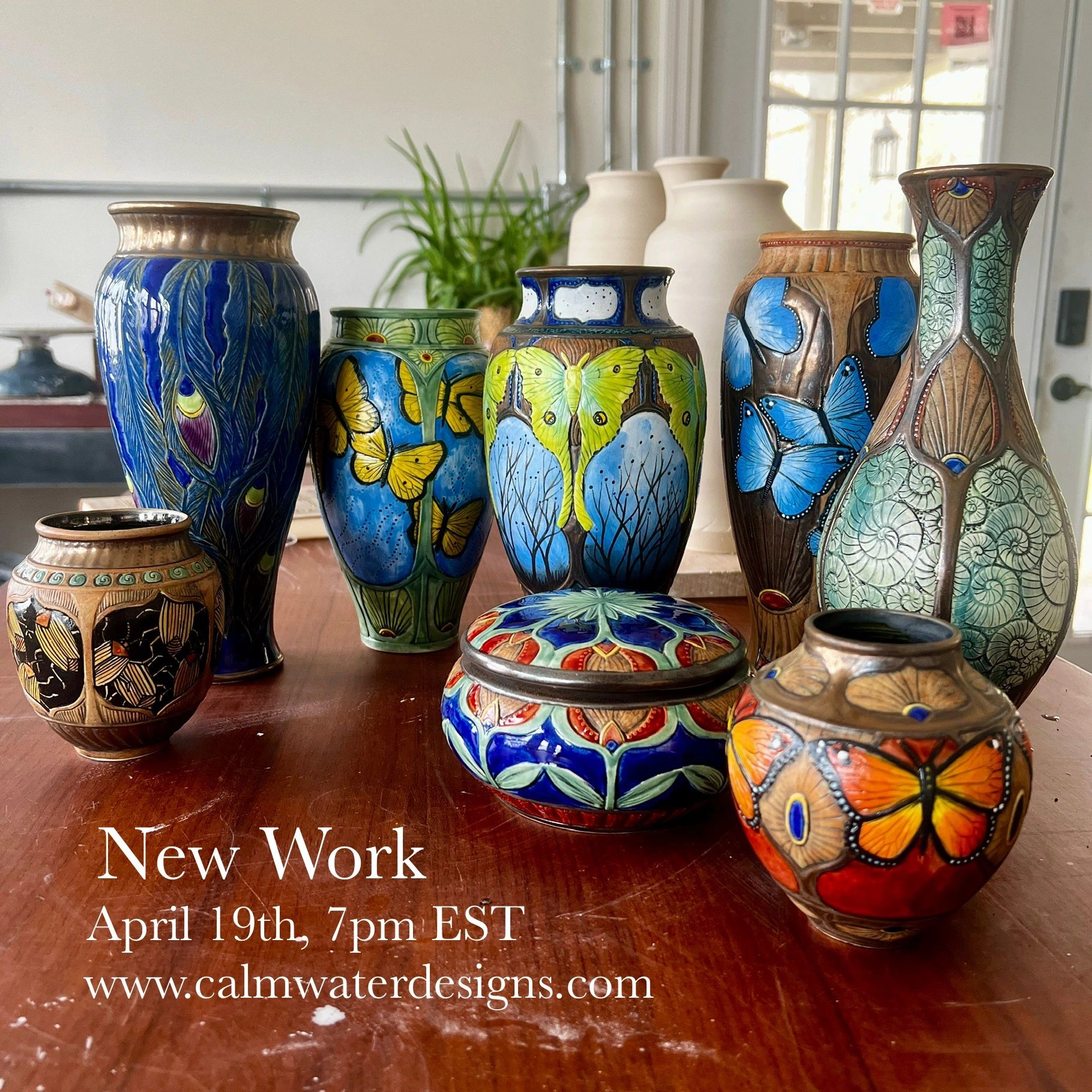 Colorful ceramic vases and pots with butterfly and nature designs displayed on a wooden table.
