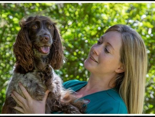 Woman holding and looking lovingly at a happy dog outdoors.