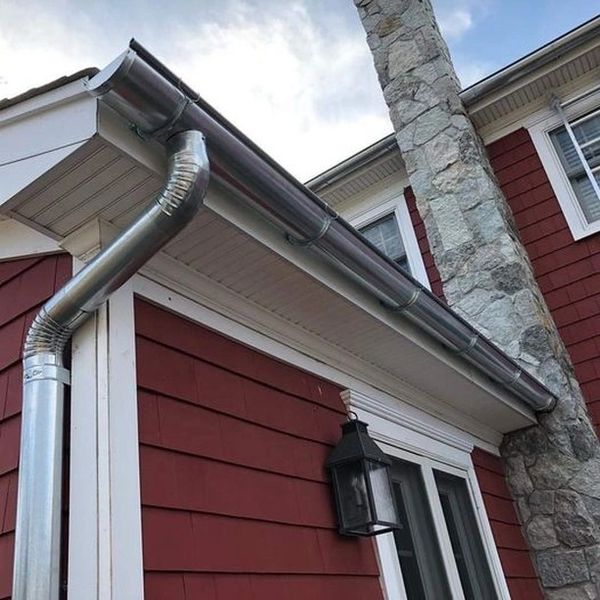 Metal gutters on corner of house with red siding.