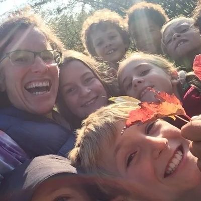 A joyful group selfie outdoors with autumn leaves.