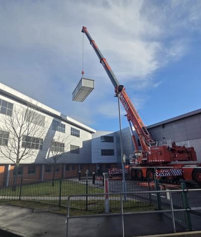 Crane lifting container near buildings.