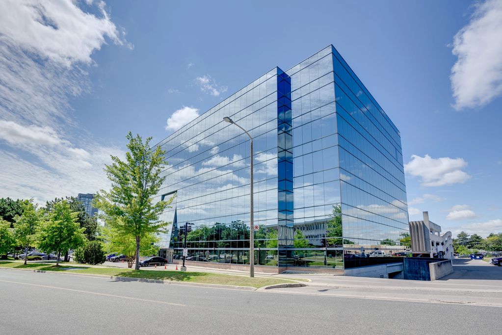Modern glass building reflecting the blue sky and trees.