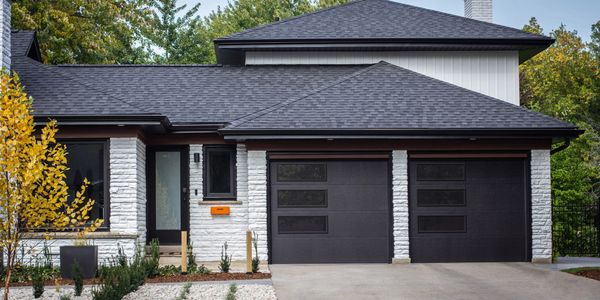 Modern house with black garage doors and a bright orange mailbox.