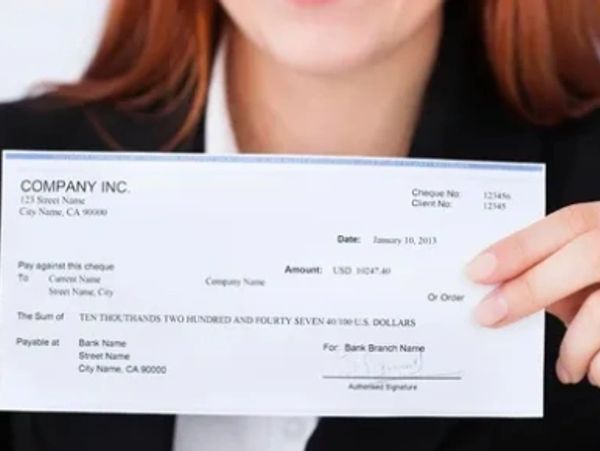 Person holding a blank company check for $10,247.40.