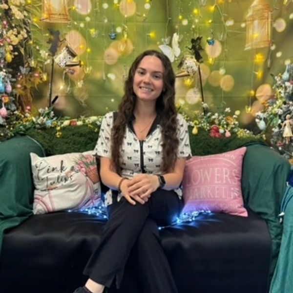 A woman sitting on a decorated sofa with floral and light decorations.