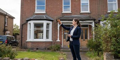 Real estate agent showing a house to potential buyers outdoors.