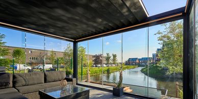 Modern glass patio enclosure overlooking a serene canal and neighborhood.