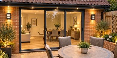 Cozy outdoor patio with a round table and plants by sliding glass doors.