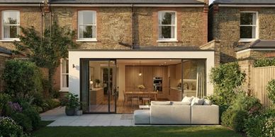 Modern home extension with glass doors opening to a cozy garden seating area.