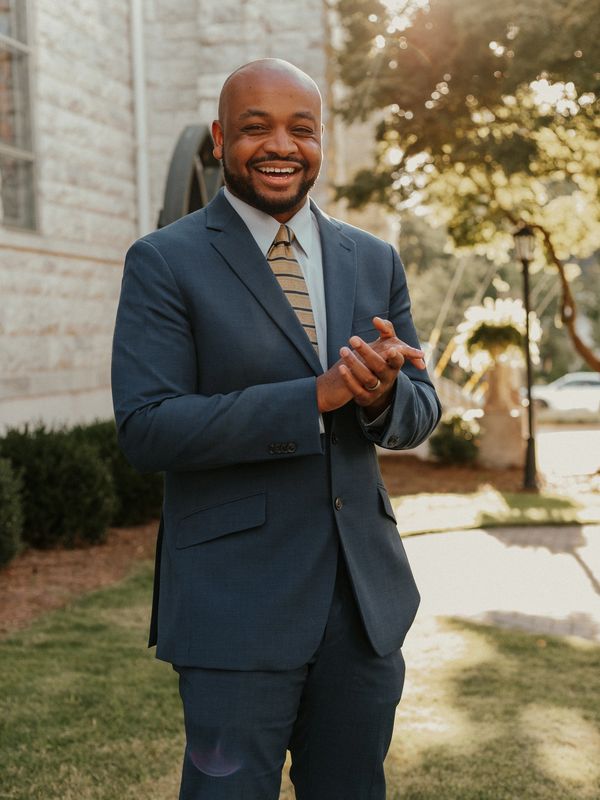 Smiling man enjoying a sunny day in front of a church, radiating happiness and positivity