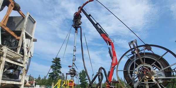 Industrial crane with large spool and machinery under blue sky.