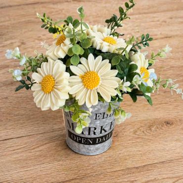 A small metal bucket with artificial daisies.