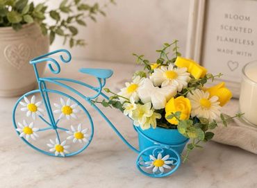 Decorative blue bicycle planter with yellow and white flowers.