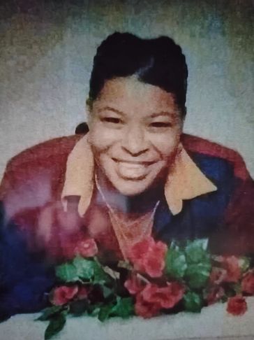 Smiling person with a bouquet of red flowers, wearing a two-tone jacket.