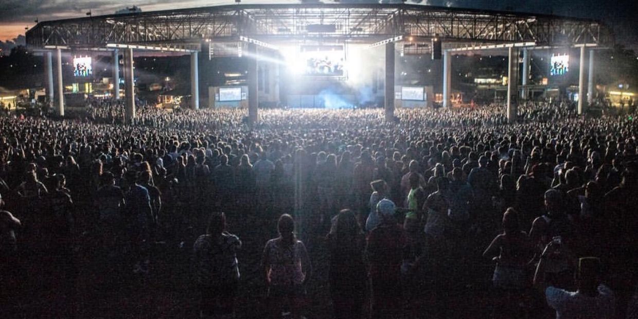Large crowd at a nighttime outdoor concert with bright stage lights.