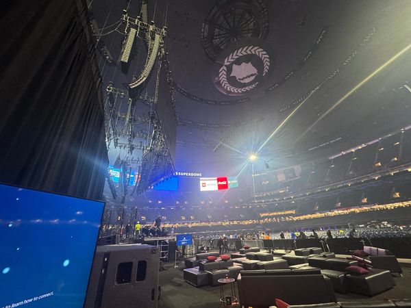 Inside a large stadium with stage setup and seating areas.
