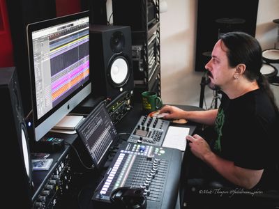 Man working on music production with audio equipment and software.