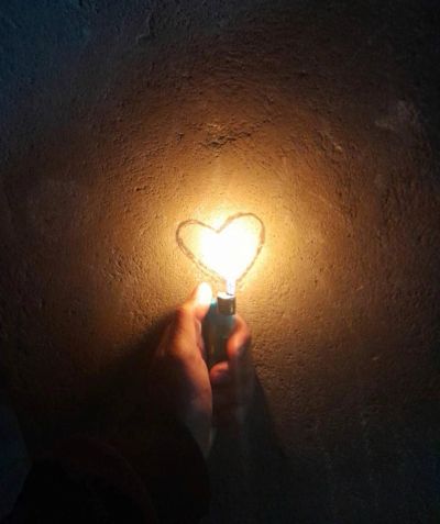 Une main tient un briquet allumé en forme de cœur.
