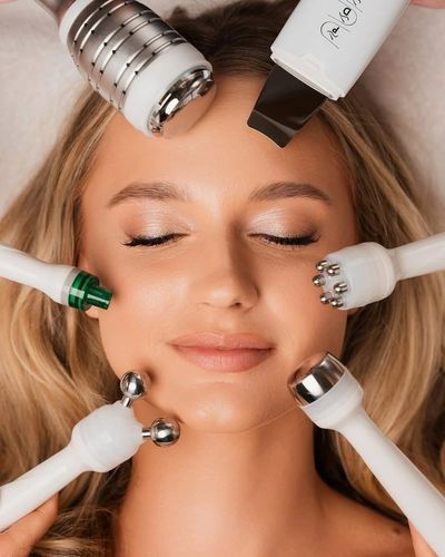 Woman receiving facial treatment with multiple devices.