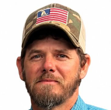 Man wearing camo hat with an American flag patch.