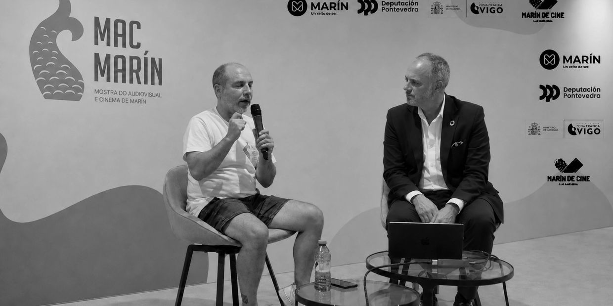 Dos hombres conversando en evento audiovisual.