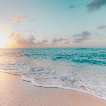 Praia tranquila com ondas suaves ao pôr do sol.