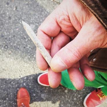 Cannabis icon Greg Williams hands a rolled cannabis joint to a friend in Vancouver, BC.