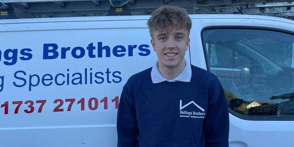 Young man standing in front of a Hellings Brothers roofing specialists van.