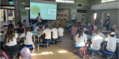 Students seated in a school assembly or classroom setting.