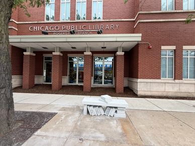Entrance of Chicago Public Library with brick exterior and stacked books sculpture.
