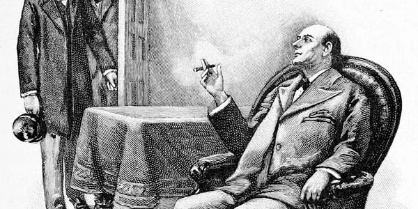 A man in a suit smoking, seated while another man stands holding a hat.