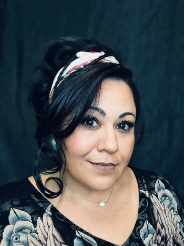 Woman with dark hair wearing a floral headband and necklace.