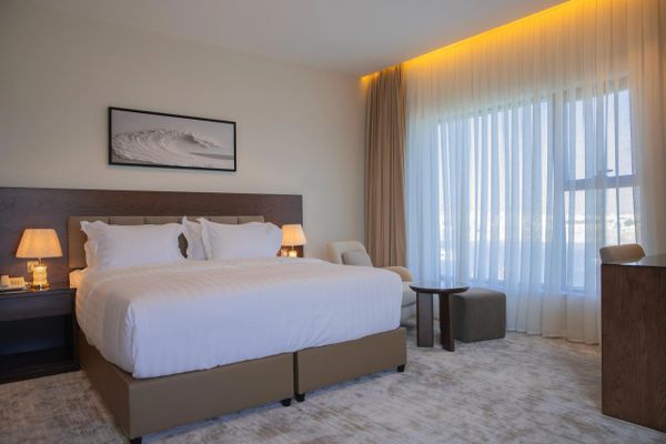 Modern hotel room with a large bed and soft lighting.