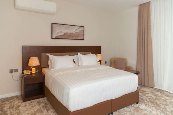 Modern hotel room with king-size bed and warm lighting.