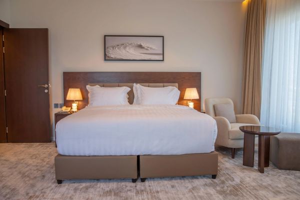 Modern hotel room with king-sized bed and cozy seating area.