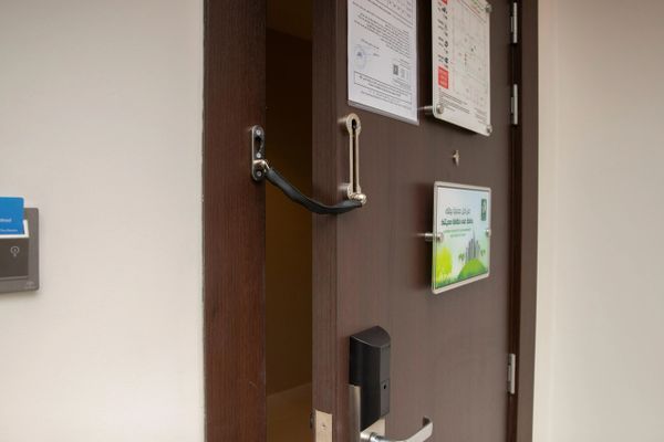 Partially open hotel door secured with a door chain and electronic lock.